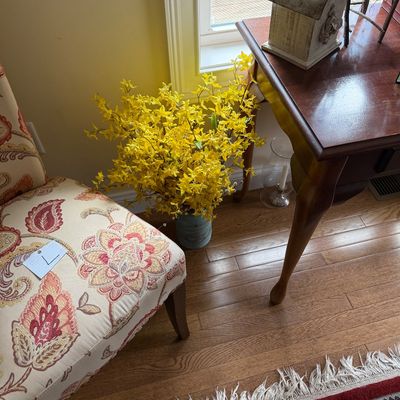 Faux yellow forsythia arrangement in a rustic blue metal bucket, displayed alongside a floral paisley upholstered accent chair.