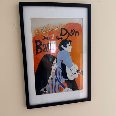 Framed concert poster featuring Joan Baez and Bob Dylan, presented in a simple black frame with white matting.