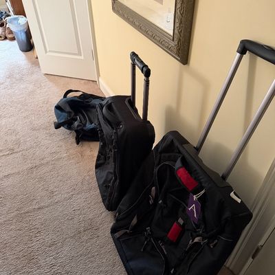 Two black rolling suitcases, including one L.L. Bean model, shown with extended handles alongside a blue duffel bag.