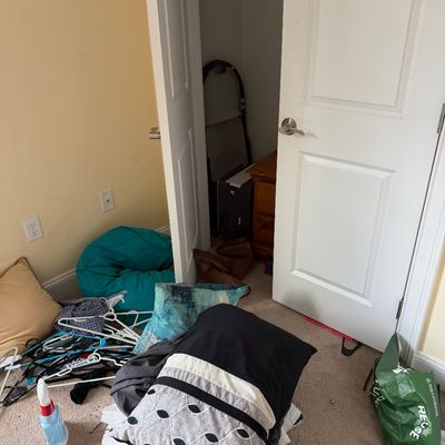 Assorted household items including a teal bean bag chair, decorative throw pillows, plastic hangers, and a green reusable shopping bag...