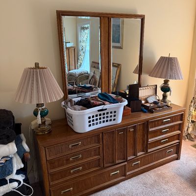 Vintage mid-century modern oak triple dresser with a matching double-panel mirror, flanked by a pair of brass and green glass table lamps...