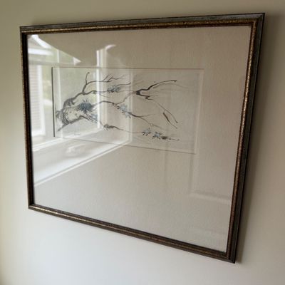 Framed and matted watercolor painting depicting delicate tree branches with small blue flowers, presented in a textured metallic frame.