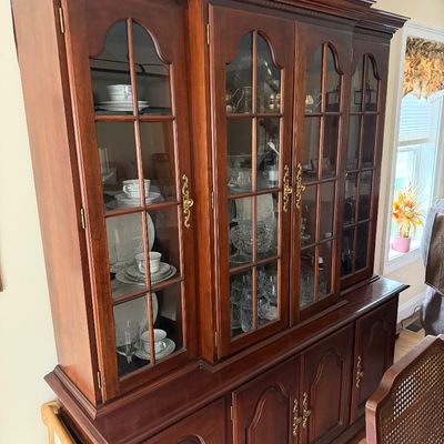 Traditional cherry wood two-piece hutch featuring arched glass cabinet doors, brass hardware, and ample lower cabinet storage.