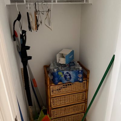 Four-drawer bamboo and wicker storage chest, shown in a closet alongside various household cleaning supplies and sundries.