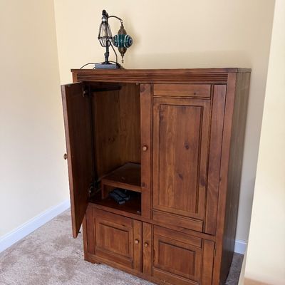 Rustic pine entertainment armoire with pocket doors, lower storage cabinets, and a warm honey finish.