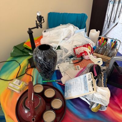 Assorted household items including a red ceramic tea set on a tray, a black and white marbled glass vase, a small desk lamp, and various...