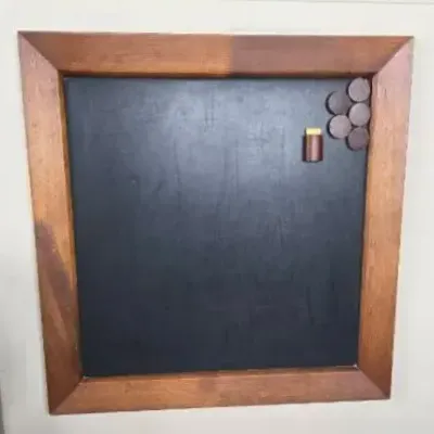 Wall-Mounted Black Chalkboard Inside A Wooden Frame With  Round Wooden Magnets And Chalk Holder