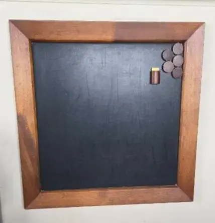 Wall-Mounted Black Chalkboard Inside A Wooden Frame With  Round Wooden Magnets And Chalk Holder