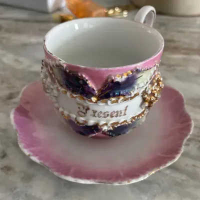 German pink lusterware teacup and saucer set featuring a raised "A Present"
