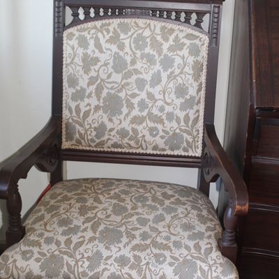 Vintage Eastlake-style dark wood armchair featuring carved spindled top trim and floral jacquard upholstery.