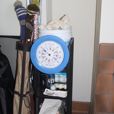 Collection of sporting goods, including a vintage golf bag with clubs and headcovers, a tide clock, golf balls, and hockey sticks.