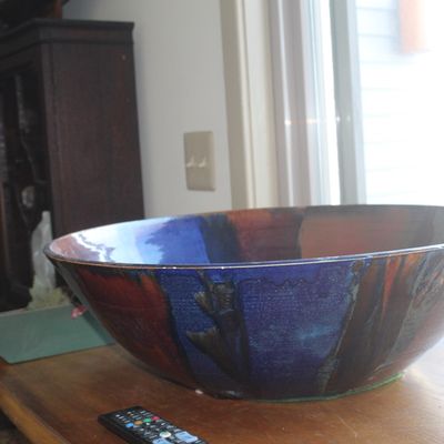 Large handcrafted studio pottery decorative bowl featuring a multi-tone drip glaze in shades of blue, burgundy, and dark grey.