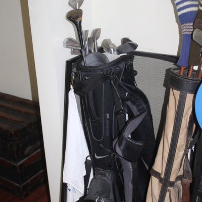 Black Nike Sport Lite stand golf bag filled with assorted clubs, alongside a vintage canvas golf bag.
