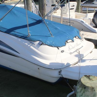 White fiberglass powerboat named "Second Chance" featuring a fitted blue canvas cover, docked at a marina pier.