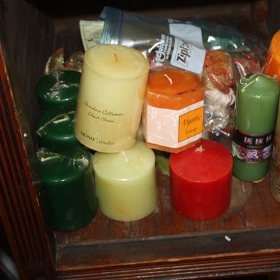 Assortment of pillar candles in various colors and sizes inside a wooden cabinet.