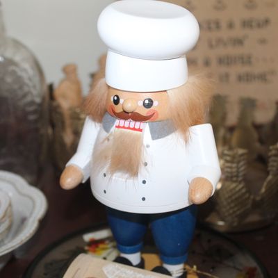 Vintage wooden chef nutcracker figurine wearing a white toque, white jacket, and blue pants.