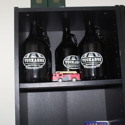 Collection of amber glass beer growlers, featuring Tuckahoe Brewing Co. and Cape May Brewing Co. logos, displayed alongside a small...
