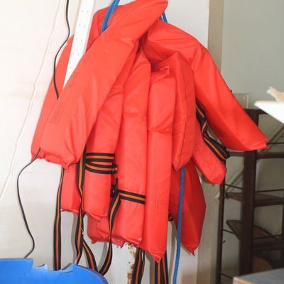 Bundle of bright orange Type II personal flotation devices hanging together by a blue rope.