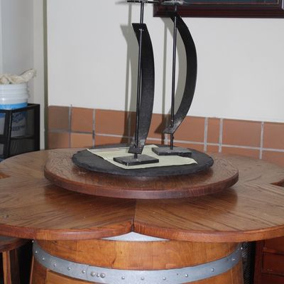 Rustic wine barrel pub table featuring a clover-shaped wooden top and lazy susan center, topped with a pair of modern black wrought iron...