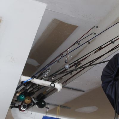 Collection of fishing rods and reels stored overhead in a garage rack.