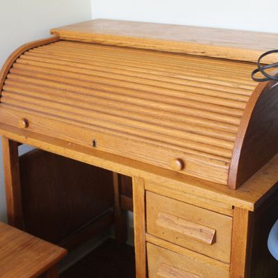 Vintage oak roll-top desk with a tambour front and side drawers, showing light surface wear.