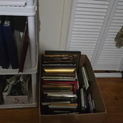 Cardboard box filled with an assortment of picture frames in various sizes, colors, and styles.
