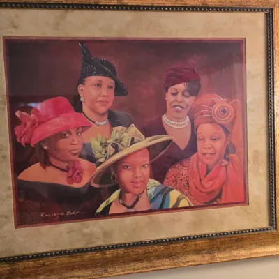 Framed art print by Kanayo Ede depicting five elegantly dressed women in hats, housed in a wide, ornate gold-finished frame.