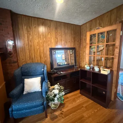 Blue patterned wingback armchair, dark wood media console with a matching mirror, and a dark brown four-cube organizer shelf in a...