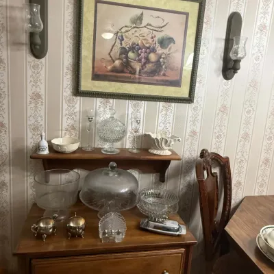 Assorted glassware and serving pieces, including a glass cake stand with dome, a trifle bowl, and a silver-plated butter dish, displayed...