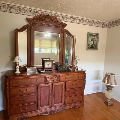 Vintage carved wood dresser with a large tri-fold mirror, featuring ornate details, multiple drawers, and a central cabinet.