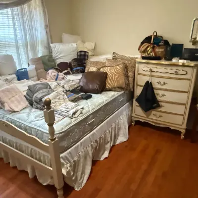 French Provincial style bedroom set including a white and gold painted wooden bed frame and matching five-drawer chest of drawers, shown...