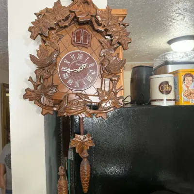 Vintage German Black Forest cuckoo clock featuring hand-carved wooden birds, maple leaves, and pinecone weights.