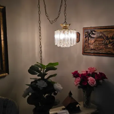Vintage Hollywood Regency style crystal prism swag lamp suspended by a brass chain over a console table.