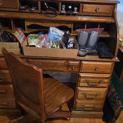 Vintage oak rolltop desk with matching cane-back swivel chair, featuring multiple drawers, cubbies, and brass hardware.