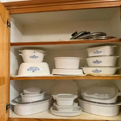 Collection of vintage CorningWare baking dishes, featuring the classic Blue Cornflower pattern and French White ribbed designs, arranged...