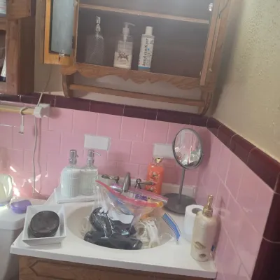 Vintage bathroom vanity with a wooden cabinet, pink tiled walls, and a matching wooden medicine cabinet above.