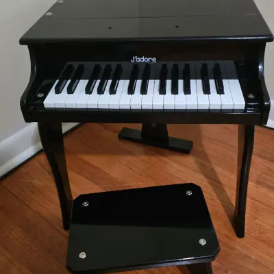J'adore Paris black wooden toy grand piano with matching bench, featuring a 30-key keyboard.
