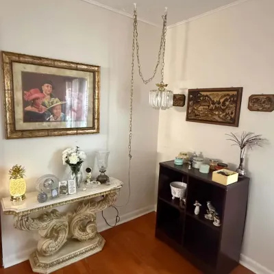 Ornate neoclassical console table with a faux-stone finish and scrollwork base, paired with a vintage swag lamp and a dark wood display...