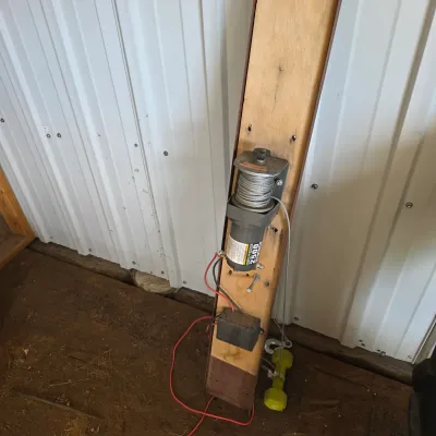 Sale Photo Thumbnail #87: Badland 2500 lb. utility winch mounted to a wooden board with wiring and a hook attached.