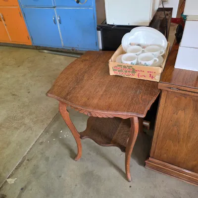 Sale Photo Thumbnail #74: Vintage two-tier oak parlor table with cabriole legs and carved apron details, holding a boxed set of mid-century Fire-King white milk glass cups and saucers.
