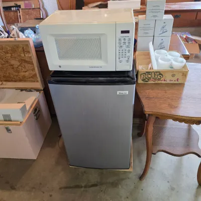 Sale Photo Thumbnail #75: Magic Chef stainless steel mini fridge paired with a white GE turntable microwave oven, both in clean, used condition.