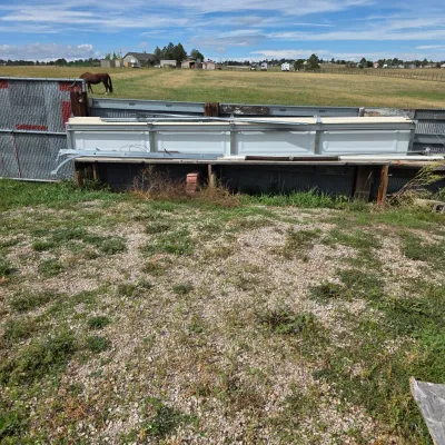 Sale Photo Thumbnail #84: Disassembled white sectional garage door panels with tracks and hardware, stored outdoors.