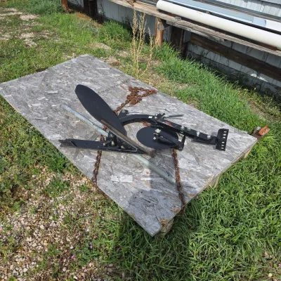 Sale Photo Thumbnail #79: Brinly-Hardy sleeve hitch moldboard plow with a coulter wheel, resting on a sheet of plywood outdoors.