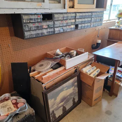 Sale Photo Thumbnail #64: Assorted workshop items, including wall-mounted plastic parts organizers, a framed landscape print, a box of water filters, and various hardware supplies.