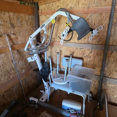 Sale Photo Thumbnail #98: Lumex patient lift system shown with a shower chair, IV pole, and other medical equipment in a storage area.