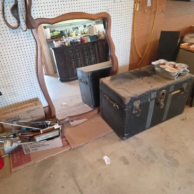 Sale Photo Thumbnail #63: Vintage black steamer trunk with metal hardware and a large wooden-framed wall mirror with a curved top.
