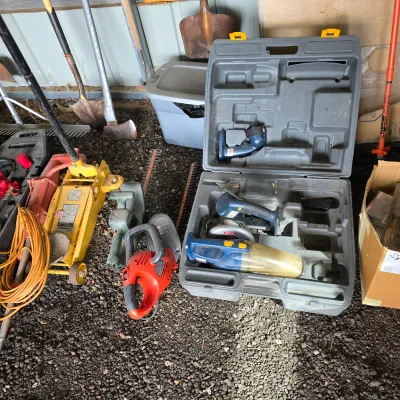 Sale Photo Thumbnail #28: Assorted garage tools including a yellow hydraulic floor jack, a red electric hedge trimmer, and a Ryobi cordless tool set in its original plastic carrying case.