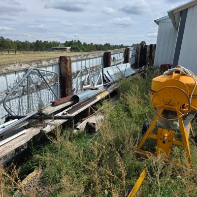 Sale Photo Thumbnail #80: Yellow portable cement mixer alongside various scrap metal, fencing, and building materials outdoors.