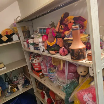 Sale Photo Thumbnail #18: Shelves filled with various holiday decorations, including Thanksgiving plush turkeys, Easter baskets, and a vintage ceramic decanter.