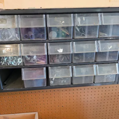 Sale Photo Thumbnail #67: Multi-drawer plastic organizer filled with various hardware, screws, and small parts, mounted above a pegboard.